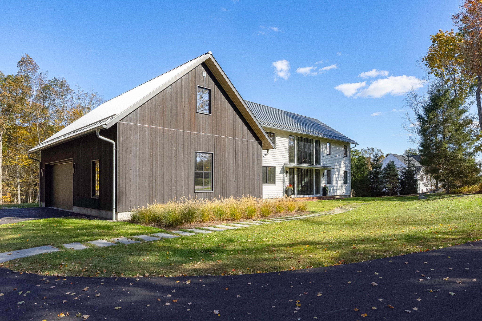 Wood-clad gable and white farmhouse exterior viewed from the driveway